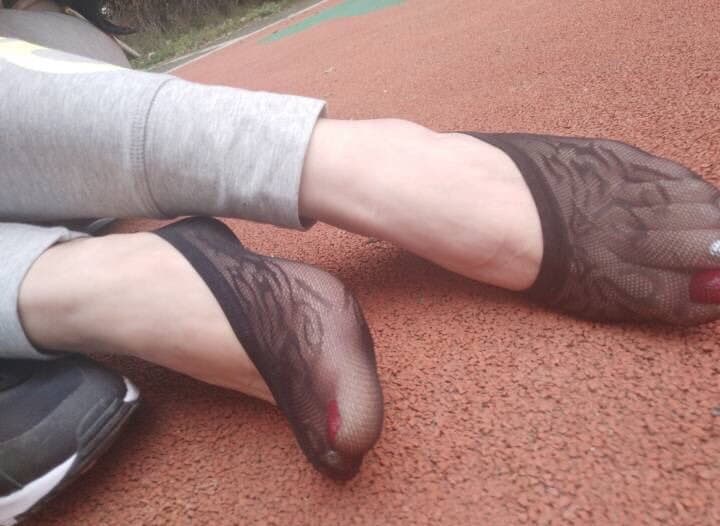 Close-up of bare feet slipping into low-cut boat socks, toes peeking out over ribbed fabric, casual seaside vibe.